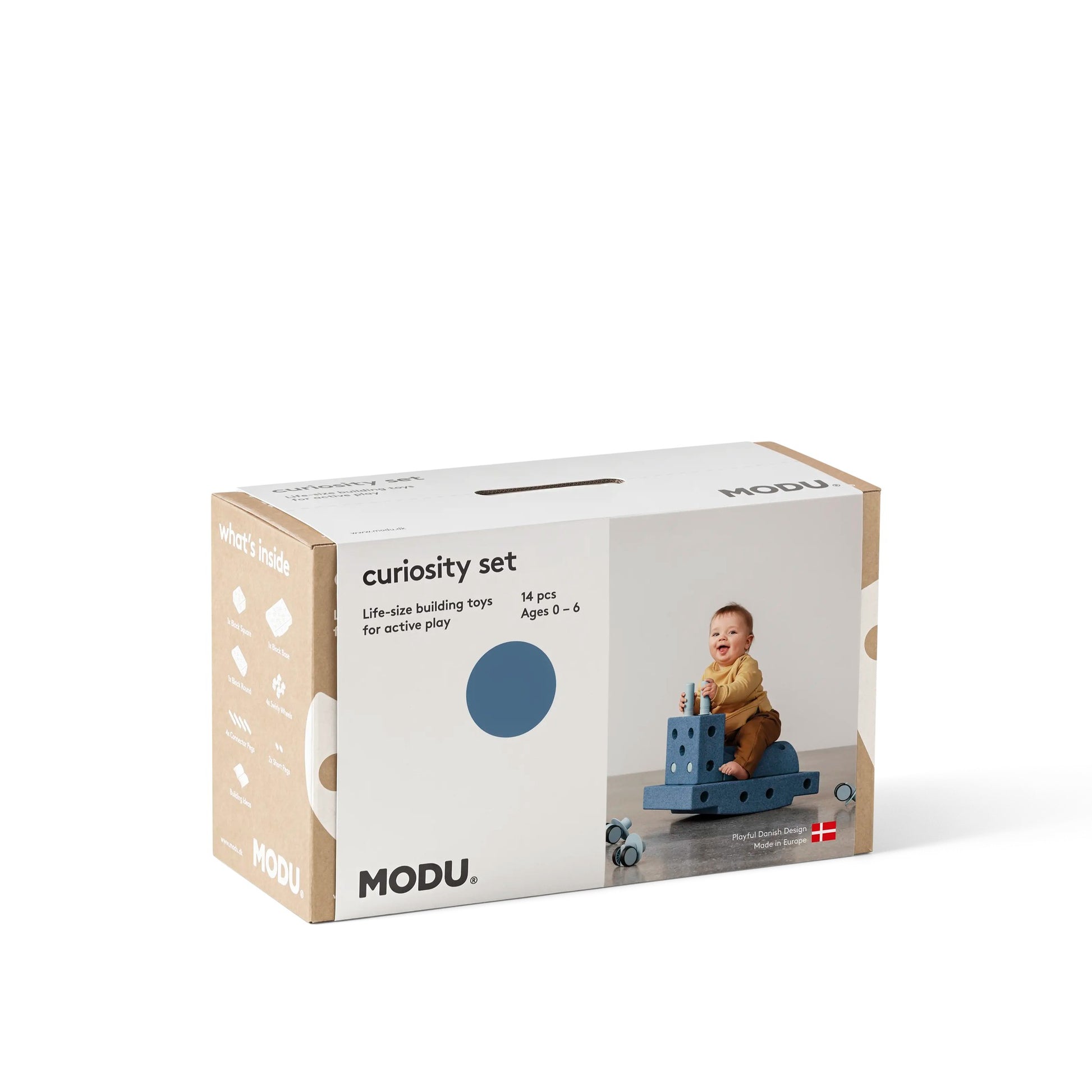 MODU Curiosity Set verpakking met kartonnen doos, toont peuter spelend op blauwe bouwblokken constructie