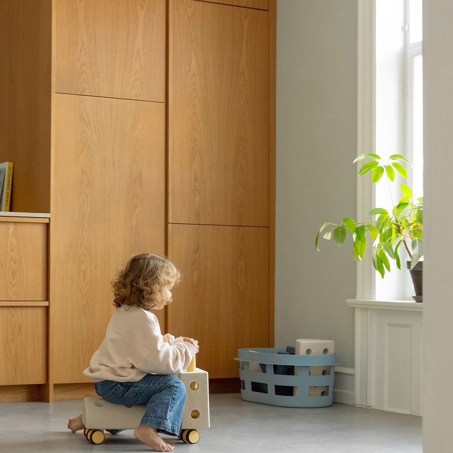 MODU Curiosity Set in gebruik: peuter zittend op houten speelelement in minimalistisch interieur met plant bij raam