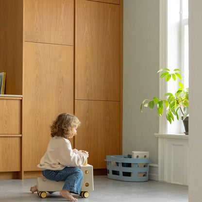 MODU Curiosity Set in gebruik: peuter zittend op houten speelelement in minimalistisch interieur met plant bij raam