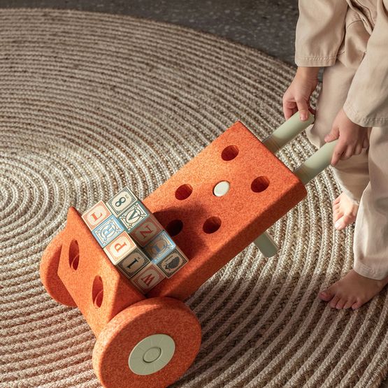 MODU Dreamer Set in Burnt Orange: kind speelt met oranje bouwblokken en wielen op gestructureerde mat, bovenaanzicht