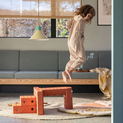 MODU Dreamer Set in Burnt Orange - kind springt op zitbank met bouwblokken op vloer in speelkamer