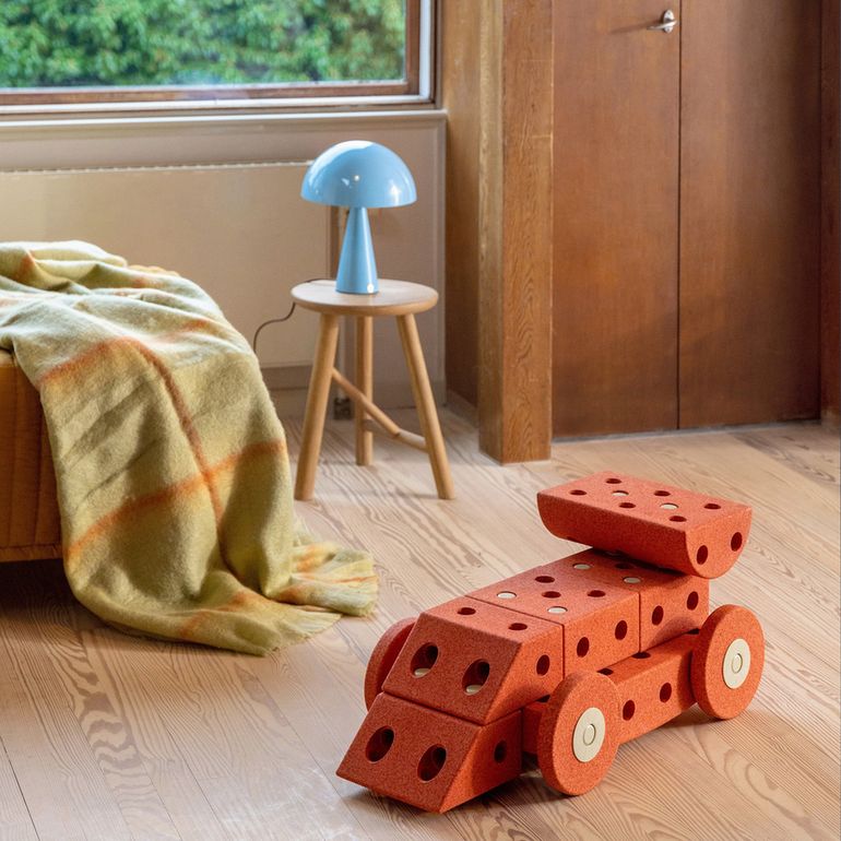 MODU Dreamer Set bouwblokken in Burnt Orange op houten vloer in kinderkamer, met blauwe lamp en bed op achtergrond
