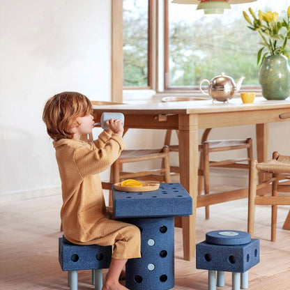 Kind zit op MODU Dreamer Set bouwblokken bij eettafel, speelgoed constructie met blauwe schuimblokken in interieur