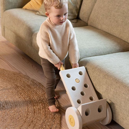 MODU Dreamer Set speelgoed: peuter speelt met zandkleurig bouwsysteem met gaten en wieltjes in woonkamer