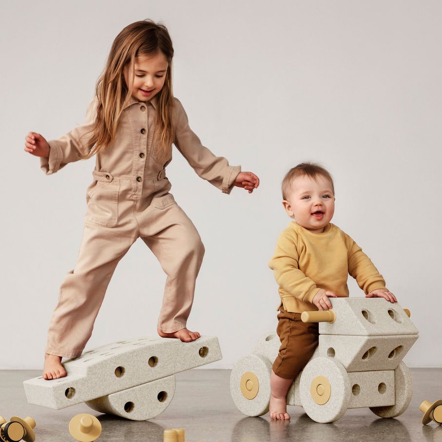 MODU Dreamer Set: twee kinderen spelen met zandgrijze schuimblokken en houtafwerking, één kind balanceert op een wiebelplank, ander kind zit op een wi
