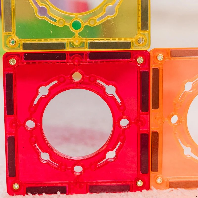 Learn and Grow Toys magnetische ballrun tegels in rood, geel en oranje, detail van ronde opening met speelgoed.