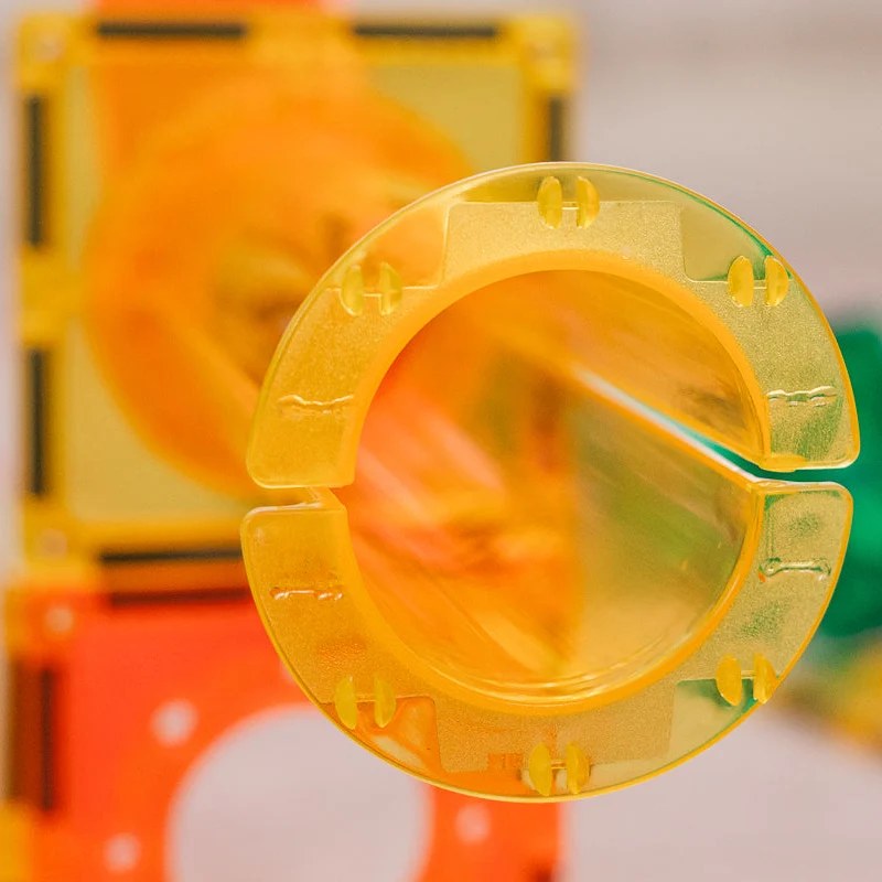 Learn and Grow Toys magnetische ballrun - gele spiraal buisbocht close-up tegen oranje bouwstenen achtergrond