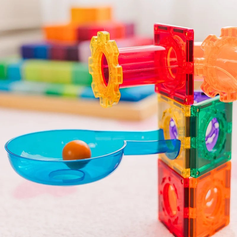 Learn and Grow Toys magnetische ballrun met geel tandwiel, rode buizen en blauwe opvangbak met oranje knikker