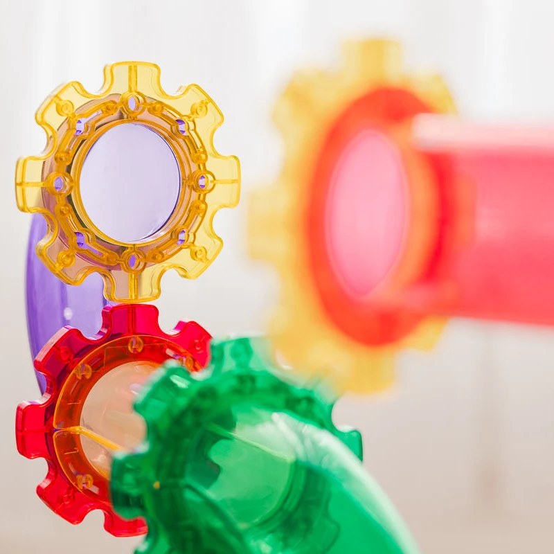 Learn and Grow Toys magnetische ballrun tegels in geel, rood en groen, close-up van tandwielen met schuine perspectief