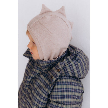 Nomenklatura Dino Balaclava in licht taupe, zijaanzicht op kind met geruit jasje - fleece bivakmuts met dino-oren