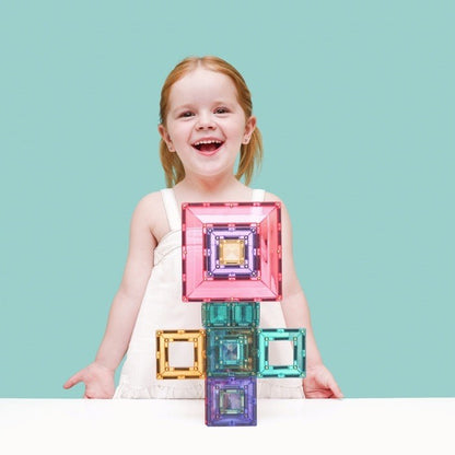 Blij meisje met rood haar toont Connetix pastel magnetische tegels in portal pack opstelling op wit tafelblad