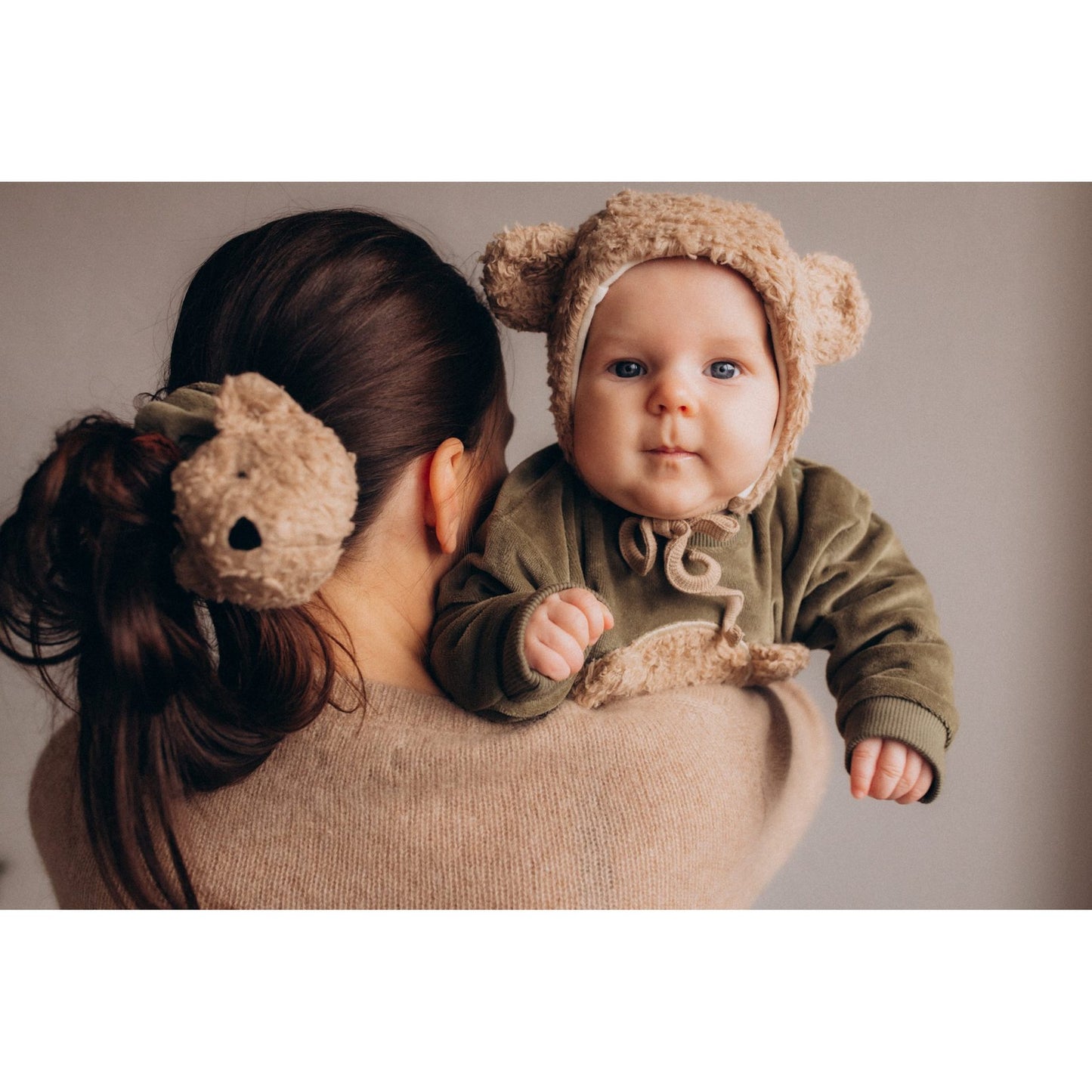Mama Nova pluche babymutsje met teddyoren, gedragen door baby van achteren gezien tegen neutrale achtergrond