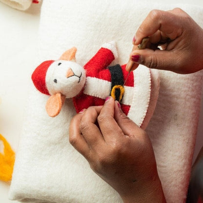 Sjaal met Verhaal kerstmuis van vilt wordt vastgehouden, detail van de rode kerstmanjas met gouden gesp