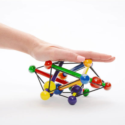 Manhattan Toy Skwish Classic rammelaar in hand, kleurrijke kralen en elastische verbindingen zichtbaar vanuit bovenaanzicht