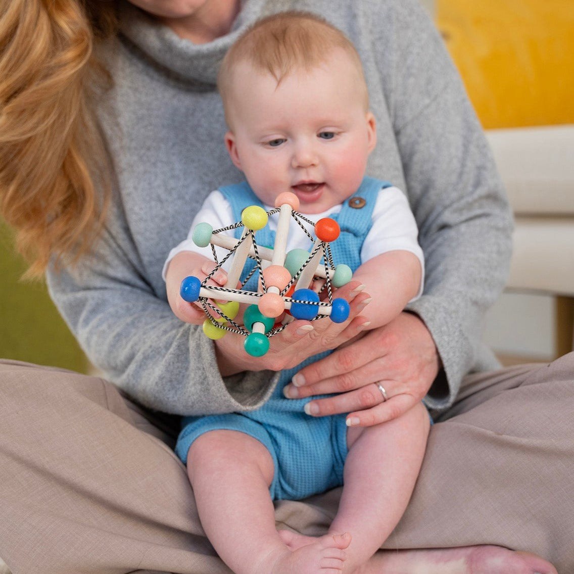 Manhattan Toy Skwish Colorpop rammelaar in handen van baby - grijpspeelgoed met gekleurde kralen en elastische koorden