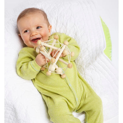 Manhattan Toy Skwish Natural rammelaar in handen van lachende baby in geel pak, bovenaanzicht