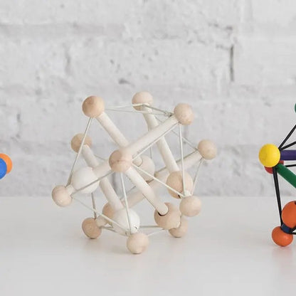 Manhattan Toy Skwish Natural rammelaar: houten bolletjes verbonden met elastische snaren, frontaal perspectief op witte achtergrond