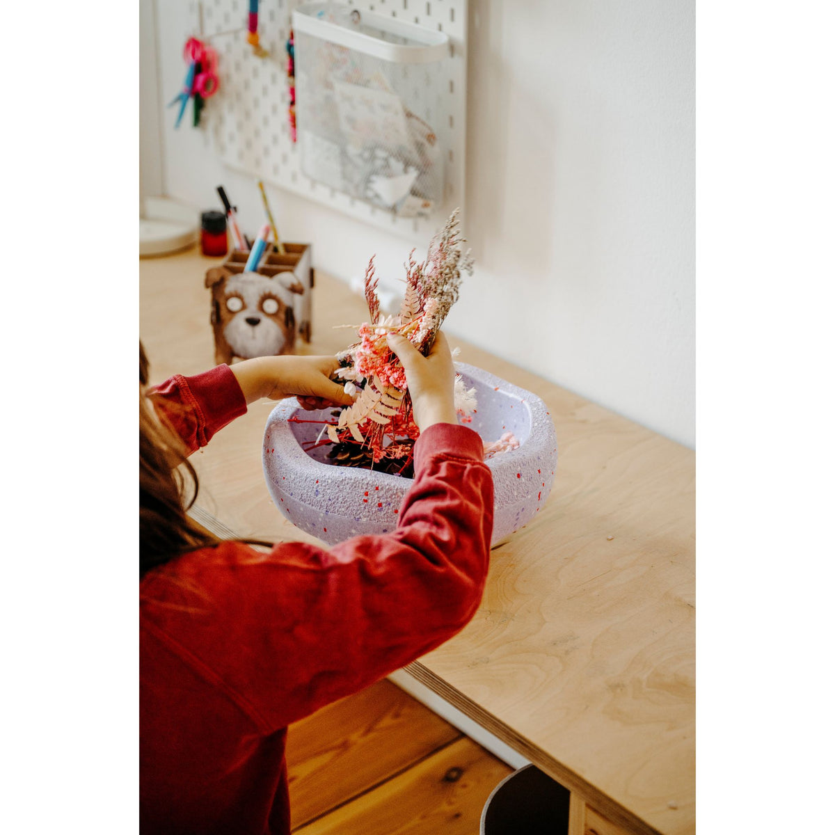 Stapelstein balanceersteen in gebruik: kind stapelt rode decoratieve elementen op de paarse steen aan houten tafel