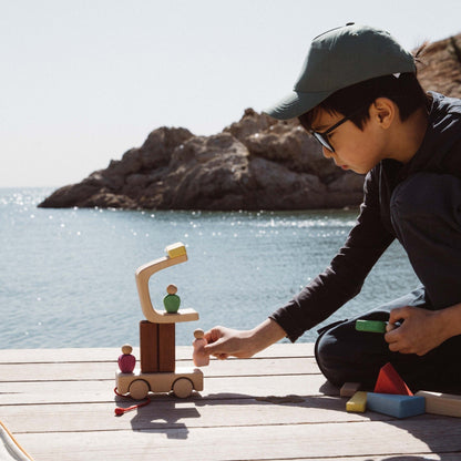 Avdar Trailer Travel Set: kind speelt met houten blokken en poppetjes aan zee met rotsformatie op achtergrond
