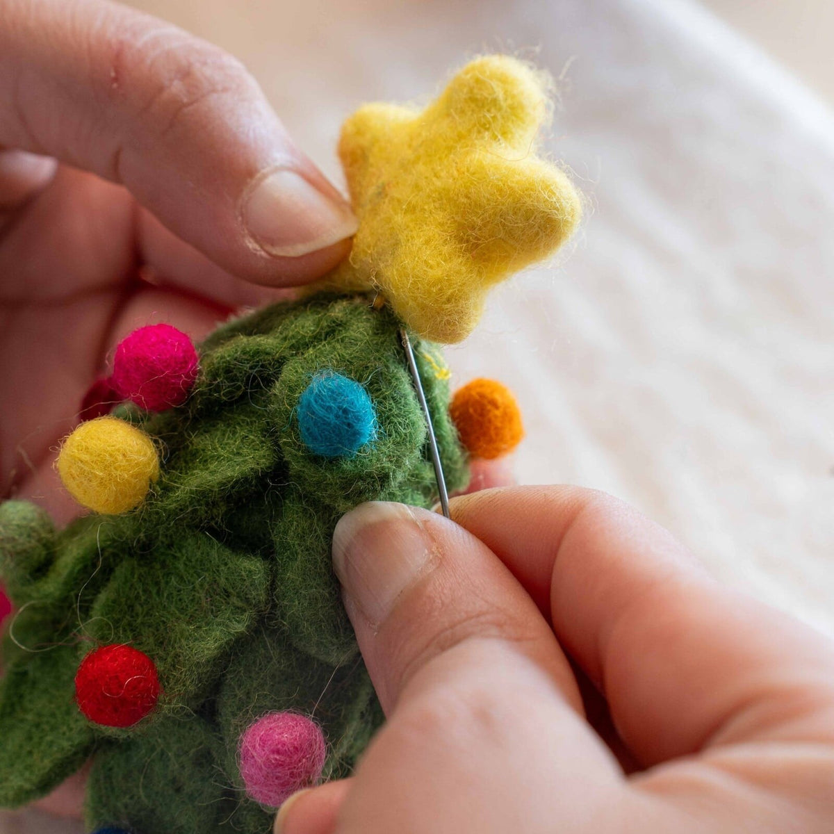 Sjaal met Verhaal vilten vingerpopje kerstboom met gele ster en gekleurde bolletjes, close-up in hand