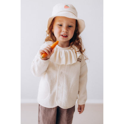 Klein meisje met rood haar draagt Wooly Organic vissershoedje met geborduurd aardbeidesign, presenteert wortel frontaal