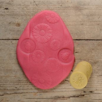 Yellow Door Let's Roll insecten kleirollen set: roze ovale stempel met bloem- en insectmotieven naast gele cilindrische roller op houten ondergrond